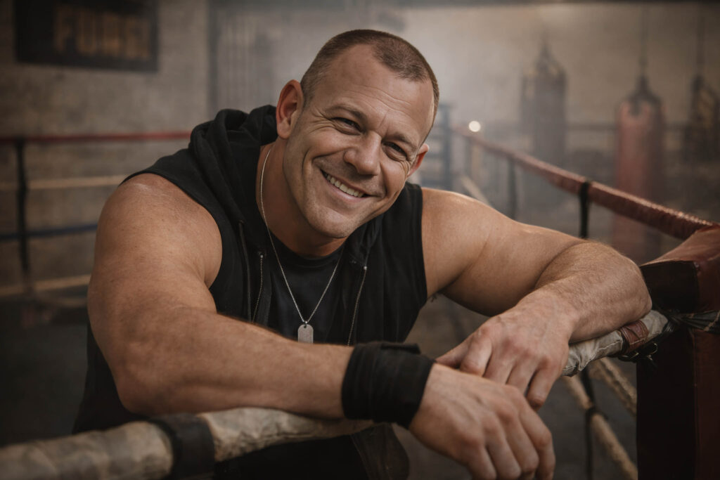 Dane Haunsby smiling while leaning on boxing ring ropes in a gym setting