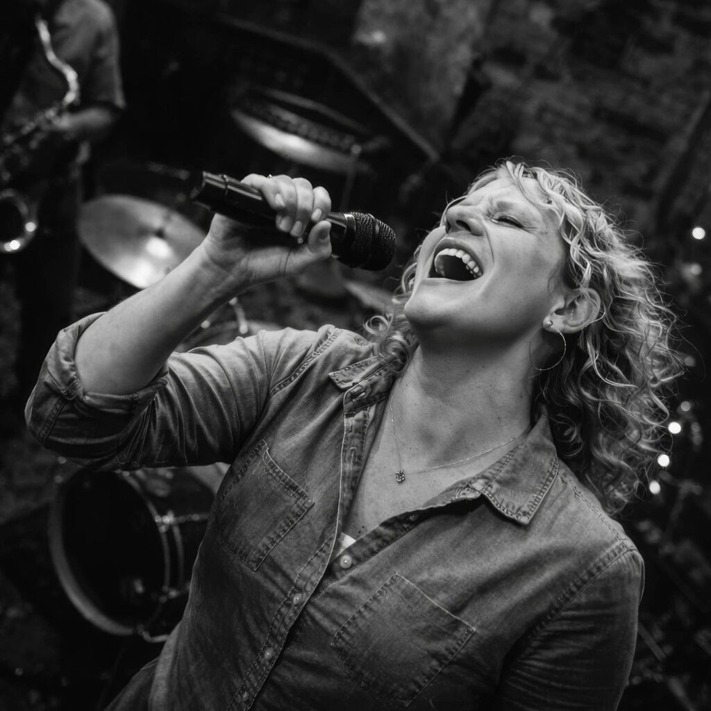 June Haunsby singing passionately into a microphone during a live performance