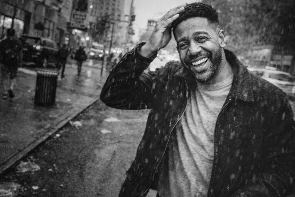 Natural portrait of Luca Haunsby laughing in the rain on a city street