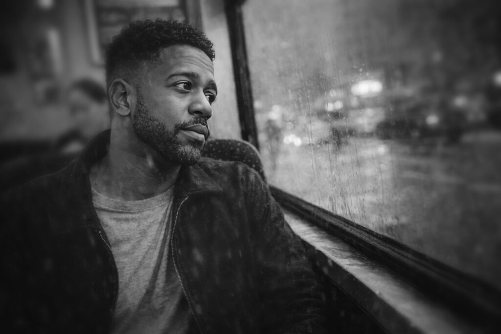 Moody portrait of Luca Haunsby looking out through a rain-covered window
