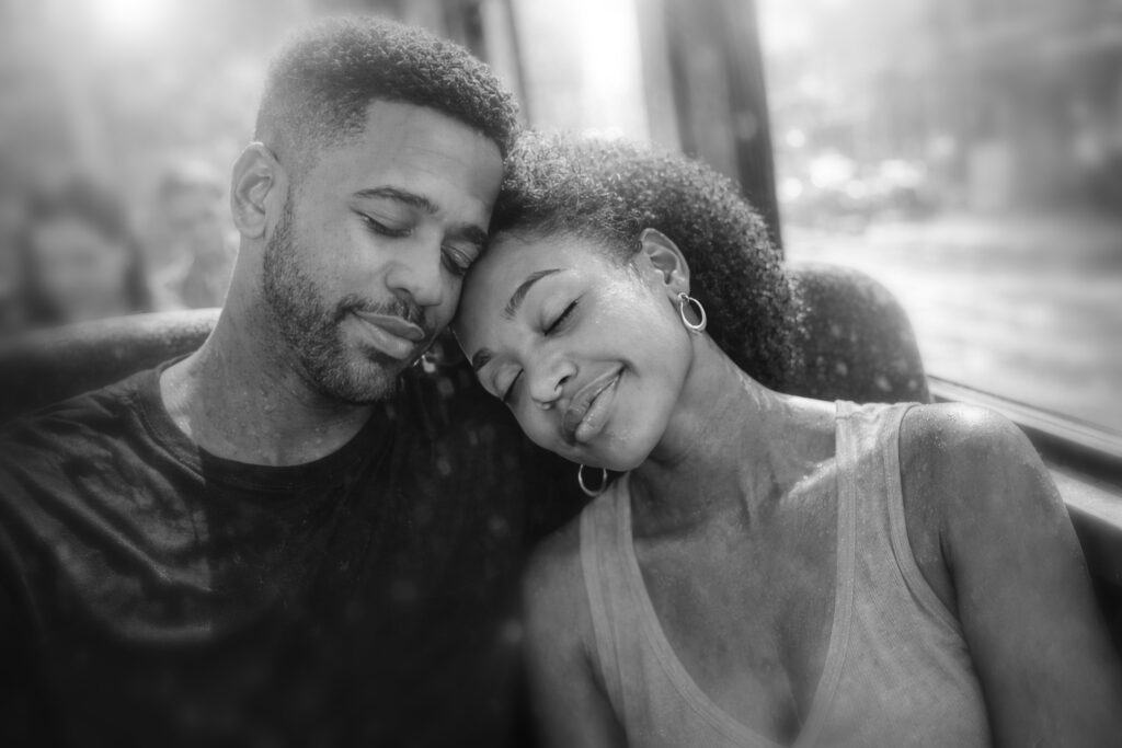 Intimate black and white portrait of Luca Haunsby and Zaya Haunsby resting together on public transport