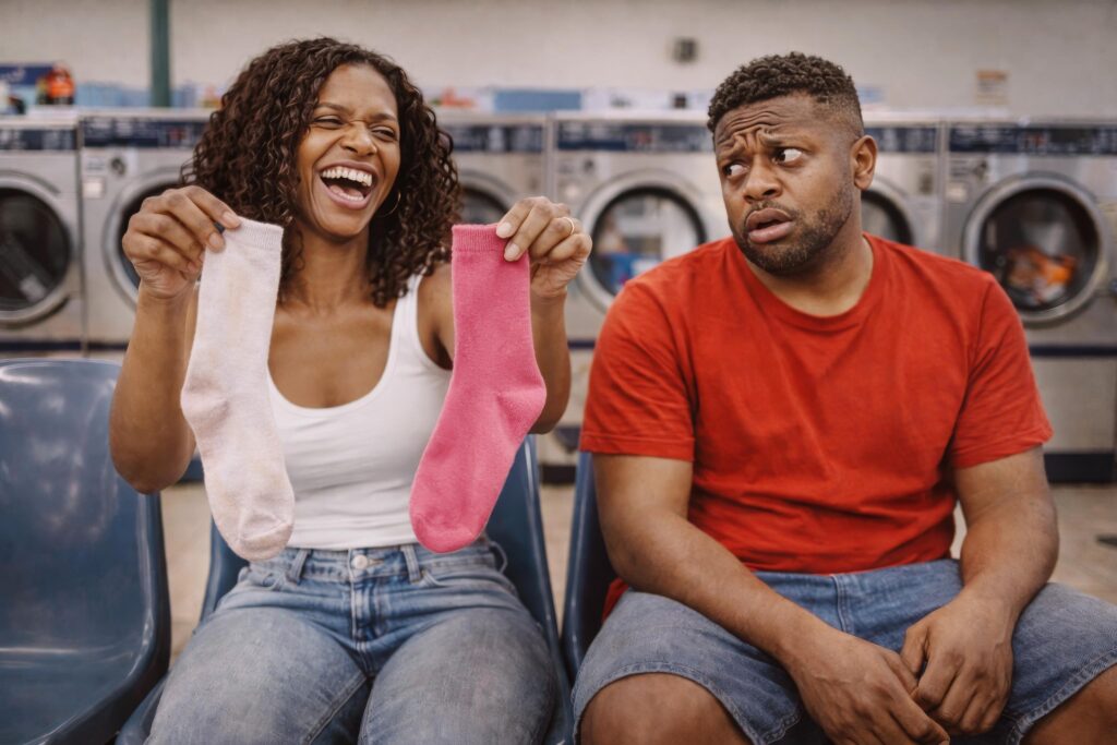 Zaya Haunsby laughing while holding mismatched socks next to Luca Haunsby in a laundromat